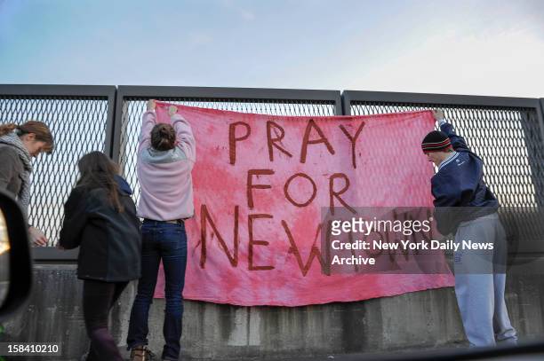 Sign reading 'Pray for Newtown' is hung above interstate following shooting at Sandy Hook Elementary school where Adam Lanza opened fire inside...
