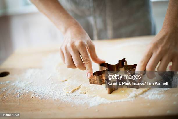 woman making organic christmas cookies, cutting dough with a cookie cutter. - cookie cutter stock pictures, royalty-free photos & images