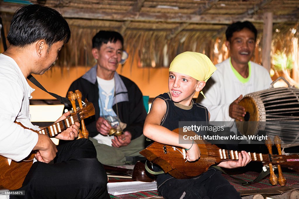 A boy plays music with locals