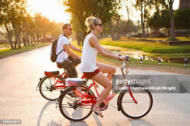 a couple goes bike riding at sunset - sukhothai stock pictures, royalty-free photos & images