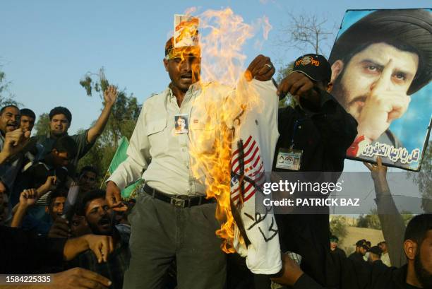 Iraqi Shiites burn a T-shirt printed with the US flag as they demonstrate against the coalition provisional authority order to close Shiite cleric...