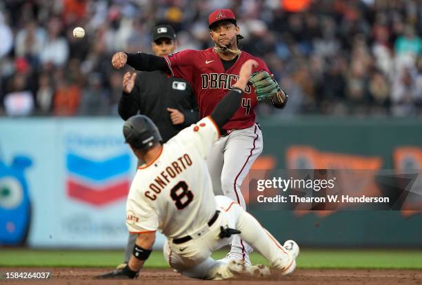 Ketel Marte of the Arizona Diamondbacks completes the double-play as he throws to first base over the top of Michael Conforto of the San Francisco...