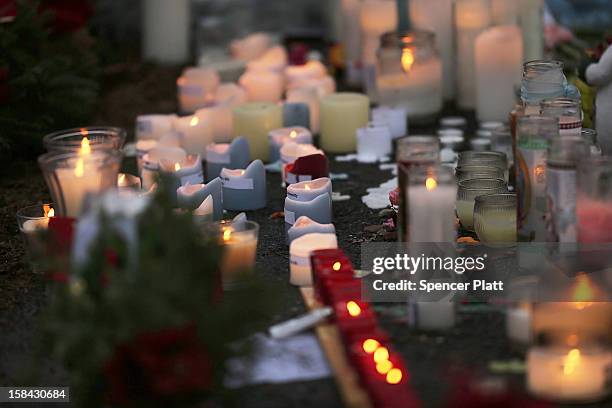 Candles are lit at a memorial in front of the Sandy Hook School December 16, 2012 in Newtown, Connecticut. Twenty-six people were shot dead,...