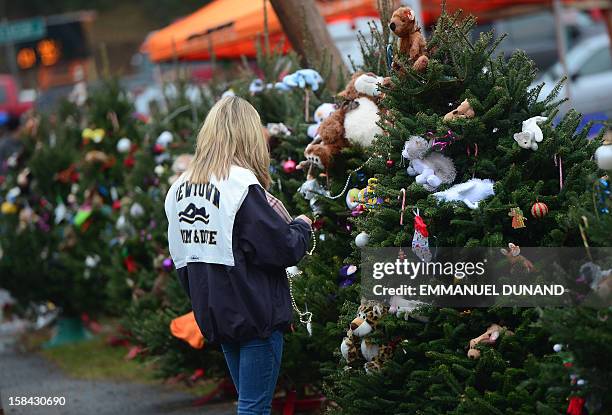 Teenager decorates Christmas trees set up at a makeshift shrine to the victims of a elementary school shooting in Newtown, Connecticut, December 16,...