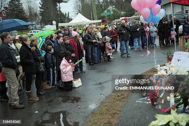 People pay their respects at a makeshift shrine to the victims of a elementary school shooting in Newtown, Connecticut, December 16, 2012. A young...