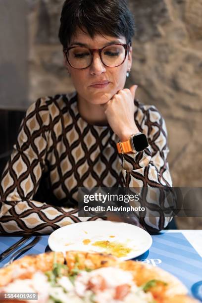 woman looking at the pizza with a doubtful face in a restaurant - picky eater stock pictures, royalty-free photos & images