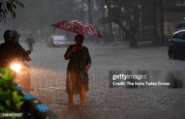 Mumbai, India – July 27: A woman holding umbrella move through a heavily waterlogged road amid rainfall in Mumbai, Maharashtra on July 27, 2023.