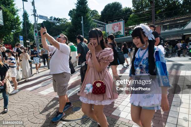 Two young ladies in cosplay outfits are entering Takeshita Street in Harujuku, as a tourist is taking a picture, in Tokyo, Japan, on August 8th, 2023.