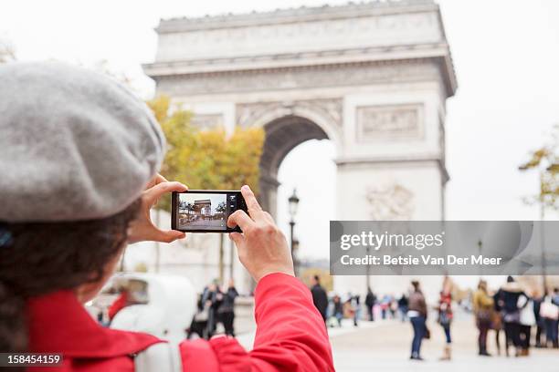 woman taking photo of the arc de triomphe,paris. - monuments paris foto e immagini stock