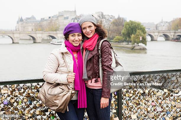 two women standing on pont des arts. - pont des arts padlocks stock pictures, royalty-free photos & images
