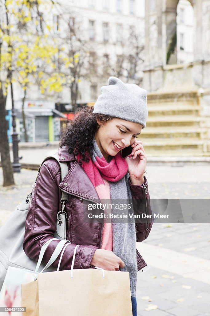 Woman on phone with shoppingbags on street,Paris.