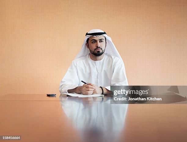 arabic businessman at a desk siging some papers - only men stock pictures, royalty-free photos & images