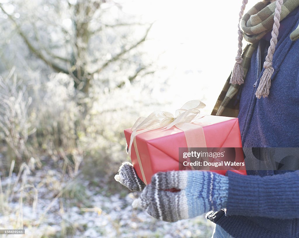 Man holding Christmas present in Winter setting.