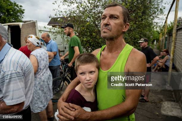 Ukrainian father Oleksandr Ustenko and his son Stanislav wait to receive a distribution of water, food, and pet food from a local charity called...