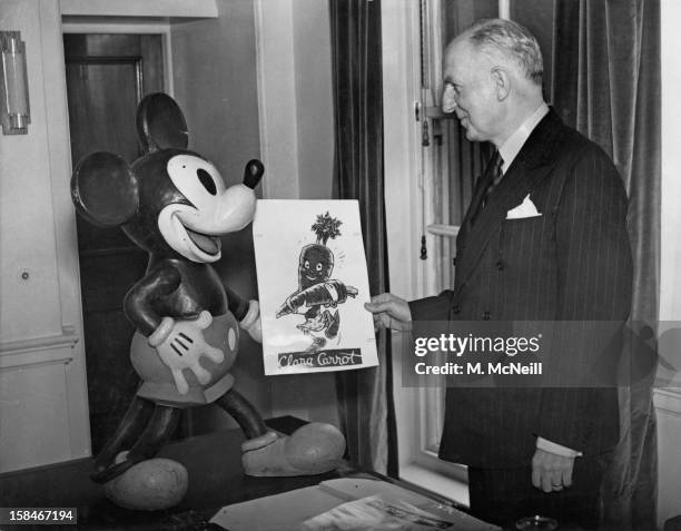 British Minister of Food Frederick Marquis , with a cartoon and a figure of Mickey Mouse sent by the Walt Disney Studios to help with the ministry's...
