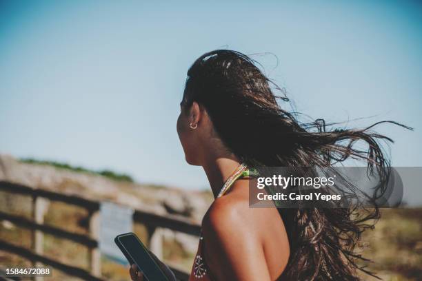 young woman with long, thick, wavy hair, walking to the beach - hair treatment stock pictures, royalty-free photos & images