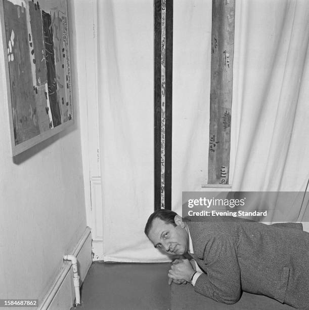 American artist Alcopley lies on the floor in front of two long and narrow paintings at a gallery in London, October 7th 1959. Alcopley's abstract...