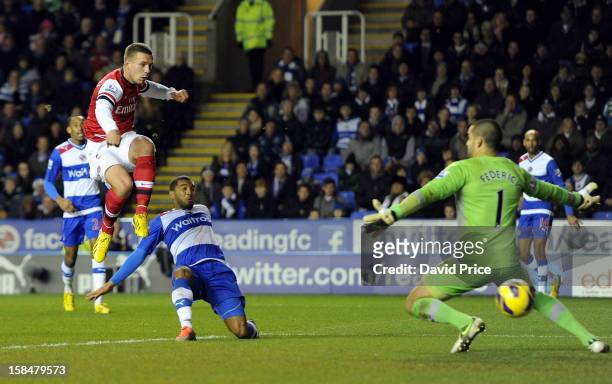 Lukas Podolski scores Arsenal's first goal past Adam Federici as Adrian Mariappa of Reading closes in during the Barclays Premier League match...