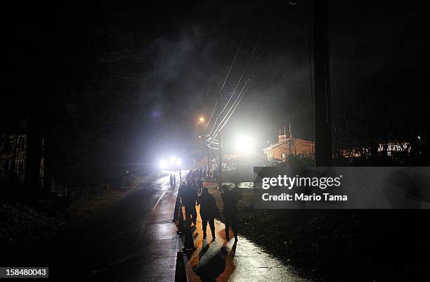 People walk through a light misty rain to a memorial for victims of the mass shooting at Sandy Hook Elementary School, on December 17, 2012 in...