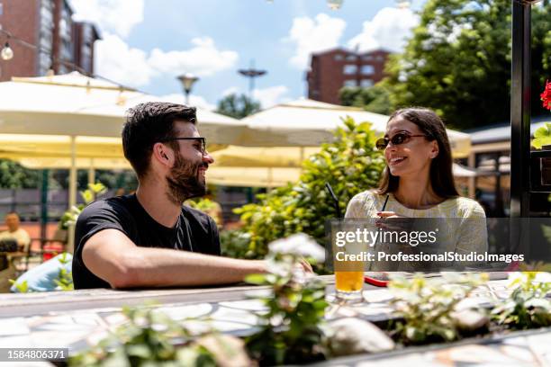 couple enjoys intimate moments amidst the tranquil setting of the cafe garden - café esplanada imagens e fotografias de stock