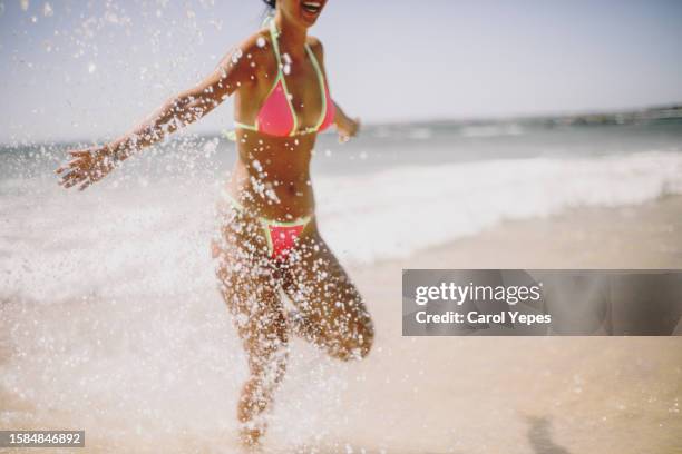 young female splashes in the ocean - hüfttief im wasser stock-fotos und bilder