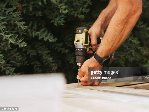 screwdriver and man building a wooden patio deck outdoors in his garden - carpentry stockfoto's en -beelden