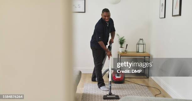 cleaning, carpet and a man with a vacuum cleaner in a home lounge for dust, dirt and maintenance. happy black male person with an electrical appliance for vacuuming in a living room for a clean house - maid hoovering stock pictures, royalty-free photos & images