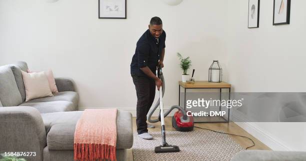 carpet, cleaning and a man with a vacuum cleaner in a home lounge for dust, dirt and maintenance. happy black male person with an electrical appliance for vacuuming in a living room for a clean house - maid hoovering stock pictures, royalty-free photos & images