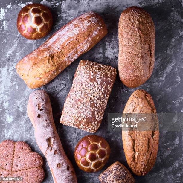 shot from above of a group of rustic and seeded breads on a textured background - fond gris stock-fotos und bilder