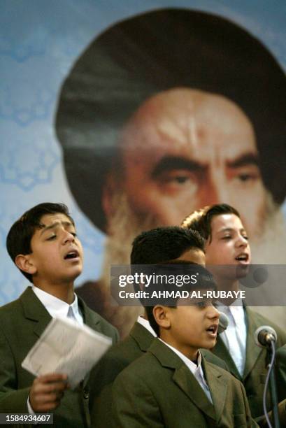 Iraqi boys sing in front of a portrait of Shiite Muslim Grand Ayatollah Ali Sistani during celebration of the al-Ghadir day attended by leader of the...