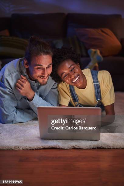 young couple enjoying a movie at home lying down in the living room floor. - the light of the moon film stock pictures, royalty-free photos & images