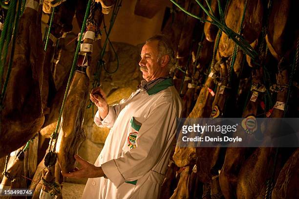 Manuel Revilla checks legs of dry-cured Jamon Iberico de bellota at his small family jamon business in the town of Guijuelo on December 14, 2012 near...