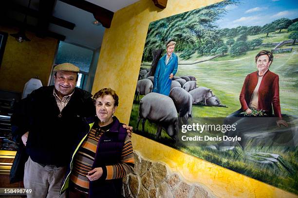 Faustino Prieto, owner of the small family-run Iberian ham business is photographed with his wife Candy Guerrero Jimenez beside a mural of themselves...