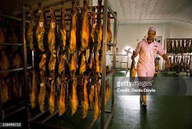 An emproyee of the company Fermin Jamones carries a leg of dry-cured Jamon Iberico de bellota in the village of La Alberca on December 14, 2012 near...