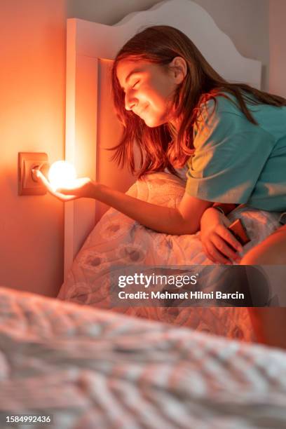 beautiful girl opening lightbulb - infrared lamp stockfoto's en -beelden