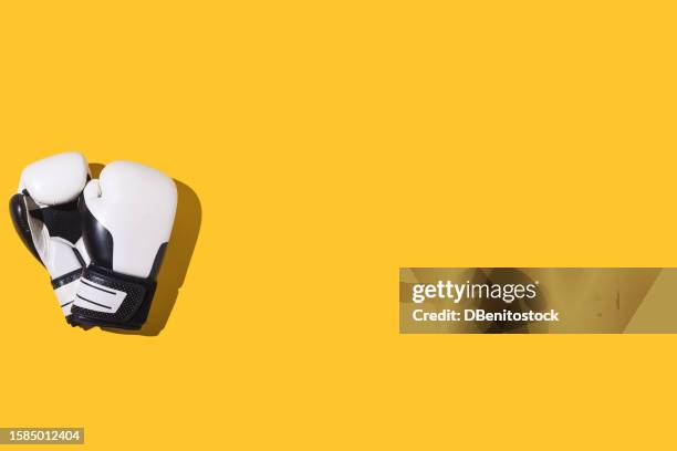 black and white boxing gloves on a yellow background. concept of boxing, sport, combat, fight, training, effort, strength, changeability and sportsmanship. - guante de boxeo fotografías e imágenes de stock