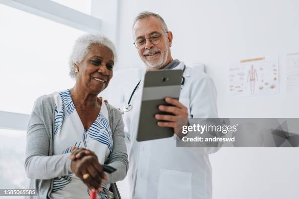 doctor attending senior patient using digital tablet - patient information stock pictures, royalty-free photos & images