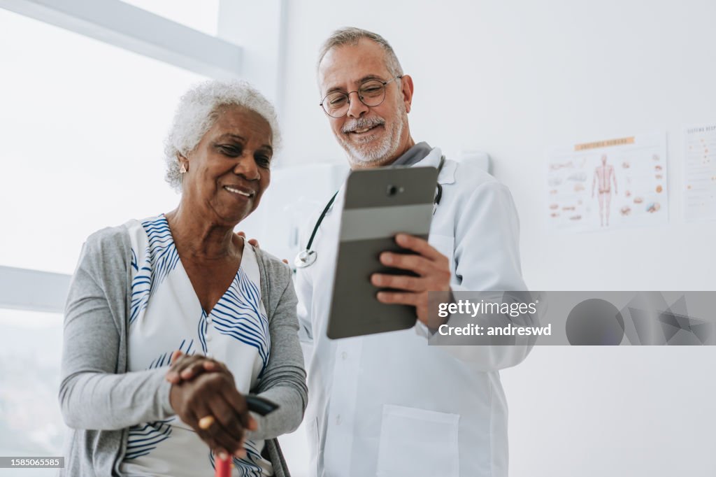Doctor attending senior patient using digital tablet