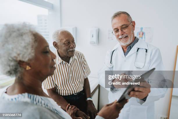 paciente en consulta médica, médico usando tableta digital - black couple married fotografías e imágenes de stock