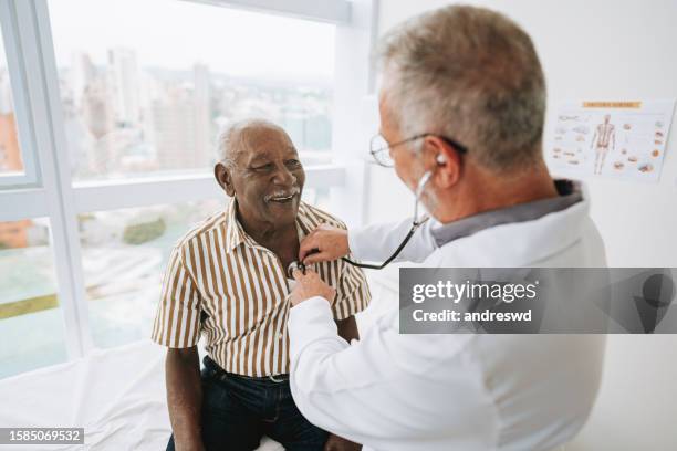 retrato de un médico escuchando los latidos del corazón de un paciente - hombres-mayores fotografías e imágenes de stock