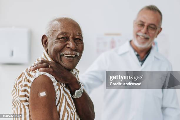 senior man bandaging vaccine on arm - shot stockfoto's en -beelden