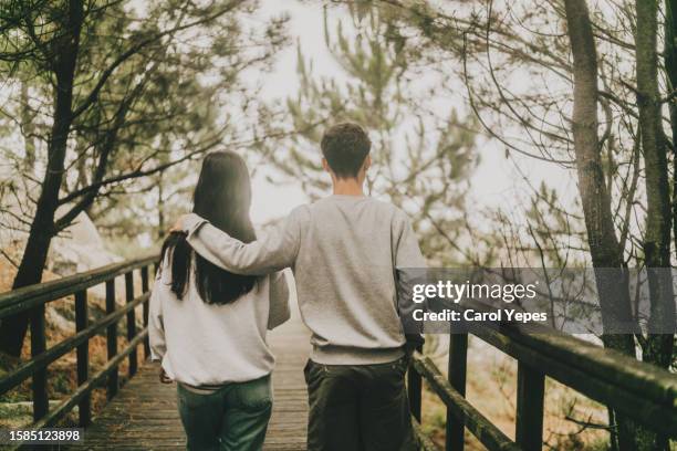 rear view  young couple in love walking in nature - tide turning stock pictures, royalty-free photos & images