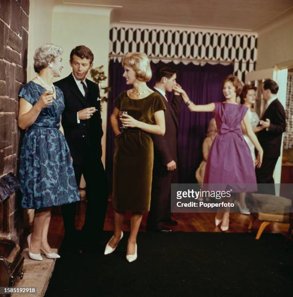 Guests chat, drink and dance at a house party in the living room of a house in England on 26th November 1960. The two women in the foreground are...