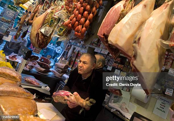 Shop worker selects a leg of jamon Iberica for a customer at the Ferpal store on Calle Arenal on December 18, 2012 in Madrid, Spain. Dry-cured...
