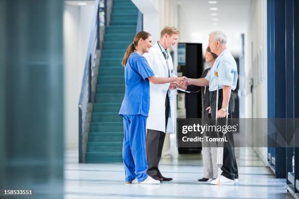 clinic staff welcomes patients - couple shaking hands with doctor stock pictures, royalty-free photos & images