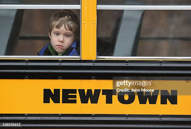 Child gazes from a school bus as it passes by the St. Rose of Lima Catholic church while mourners gathered for a funeral service for shooting victim...