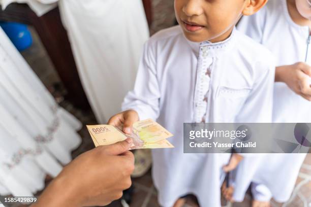 children receiving pocket money on idul fitri celebration - presents 20 years of giving stock pictures, royalty-free photos & images