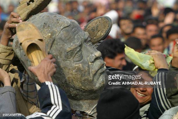Iraqi men beat a bust of ousted president Saddam Hussein following Friday noon prayers in Sadr City, a predominately Shiite suburb of Baghdad 26...