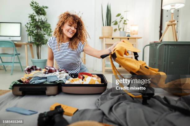 giovane donna allegra che prepara la valigia per un viaggio a casa - imballare foto e immagini stock