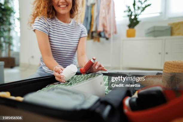 close up shot of young woman packing medicine and asthma inhaler in her suitcase - packing stock pictures, royalty-free photos & images